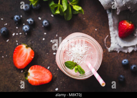 Strawberry coconut smoothie in jar with pink drinking straw, top view, selective focus. Healthy lifestyle, detox, dieting, clean eating, vegan, vegeta Stock Photo