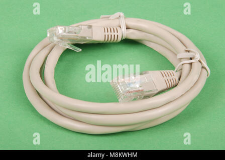 Patch cord grey network cable with molded RJ45 plug, isolated on a green background Stock Photo