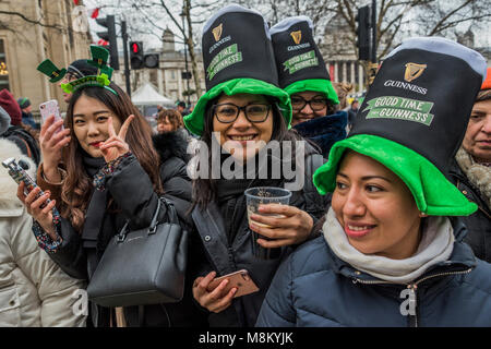 Visitors in many types of green hats are well wrapped up against the cold as they watch the parade go by -  the London St Patrick's Day parade from Piccadilly to Trafalgar Square. Credit: Guy Bell/Alamy Live News Stock Photo