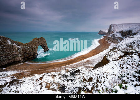 Lulworth, Dorset, UK.  18th March 2018.  UK Weather.  Durdle Door on the Jurassic Coast of Dorset with a covering of snow after a morning of heavy wintery showers.  Picture Credit: Graham Hunt/Alamy Live News. Stock Photo