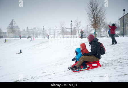 18th March 2018, Poundbury, Dorchester, Dorset, England. UK Weather. People in Dorchester in Dorset enjoying some sledging on the Great Field, Poundbury as the heavy snow falls caused by the cold air from the Beast From The East  © David Partridge / Alamy Live News Stock Photo