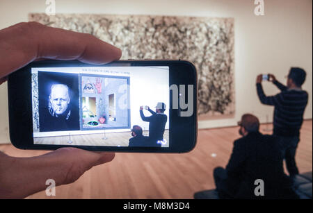 13 March 2018, USA, New York: An app for the 'MoMAR' virtual gallery on a mobilephone shows on the display digital art overlaying the painting 'One: Number 31, 1950' of US artist Jackson Pollock at the Museum of Modern Art (MoMA). Photo: Johannes Schmitt-Tegge/dpa Stock Photo