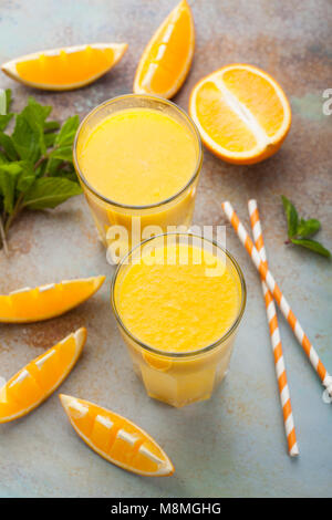 Two glasses with freshly squeezed orange juice and mint on an old rusty blue background. Top view Stock Photo