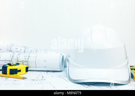 protective helmet, blueprint rolls and engineering instruments on table. architect workplace background. Stock Photo