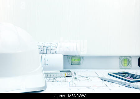 measuring instruments, pencil, calculator, safety helmet and blueprint rolls on desk. contractor workplace. Stock Photo
