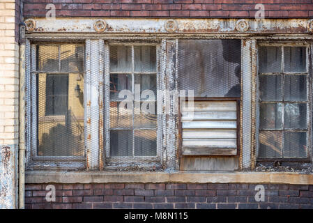 chicken wire covering old abandoned factory building windows in inner city Stock Photo