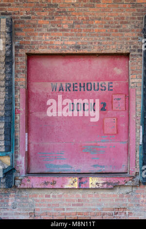old rustic red warehouse dock door on brick wall Stock Photo