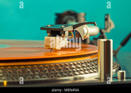Closeup of turntable needle on spinning orange colored vinyl record Stock Photo