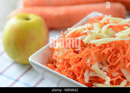 Healthy salad concept - grated carrot with apple in a white platter in close-up Stock Photo