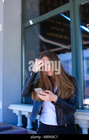 Young girl typing by smartphone at street cafe. Stock Photo
