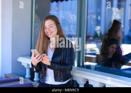Beautiful woman chatting by smartphone at street cafe. Stock Photo