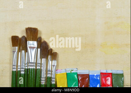 Paint brushes and used color tubes isolated on a cream background Stock Photo