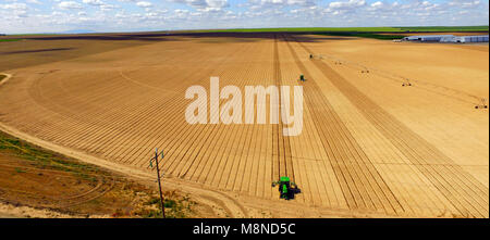 Farm Workers Work the Tillers on a smooth well cultivated field Stock Photo