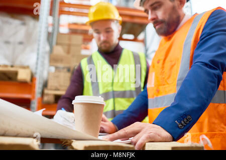 Waist up portrait of two workers studying documentation on site, focus on foreground, copy space Stock Photo