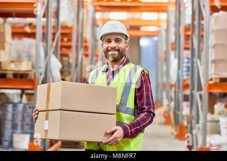 Waist up portrait of mature warehouse worker holding cardboard box smiling happily and looking at camera while doing shipping and deliveries, copy spa Stock Photo