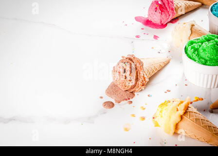 Different homemade melting ice cream in bowls and waffle ice cream cones, white vanilla, orange, pink berry, green, blue, chocolate white marble backg Stock Photo