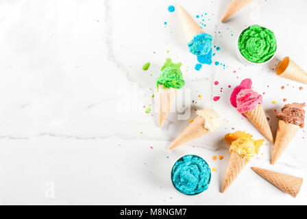 Different homemade melting ice cream in bowls and waffle ice cream cones, white vanilla, orange, pink berry, green, blue, chocolate white marble backg Stock Photo