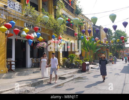Hoi An, Vietnam - MARCH 17, 2018: Happy couple of tourists on the street early morning in the old town center of Hoi An Vietnam with view of shops Stock Photo