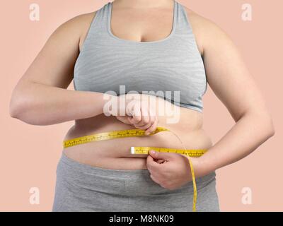 Overweight woman measuring her waist with a tape measure. Stock Photo