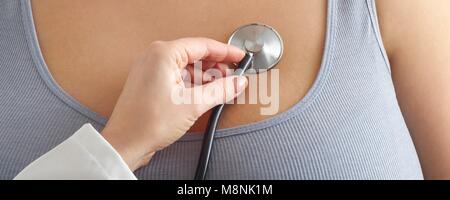 Doctor placing stethoscope against overweight woman's chest. Stock Photo