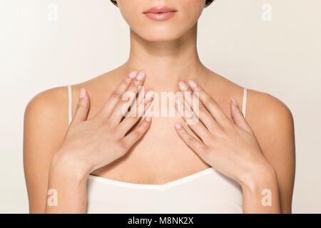 MODEL RELEASED. Young woman touching upper chest, cropped portrait. Stock Photo