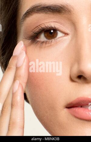 MODEL RELEASED. Young woman with fingers touching skin near eye, portrait. Stock Photo