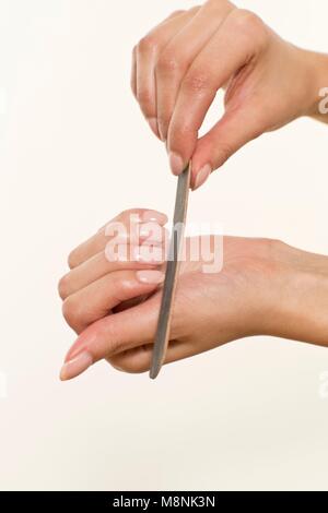 MODEL RELEASED. Young woman filing fingernails with emery board. Stock Photo