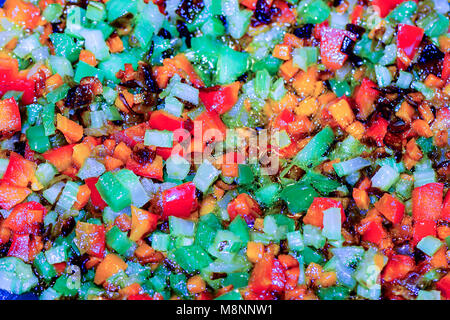 Finely chopped different and colorful vegetables in the process of stewed in olive oil in a frying pan Stock Photo