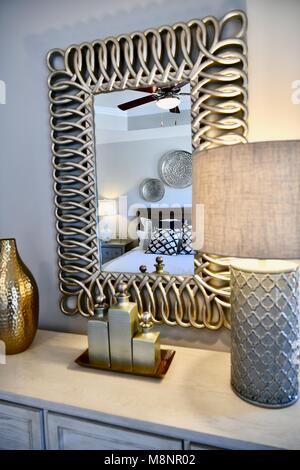 Modern bedroom dresser with gold accented decor and mirror above Stock ...