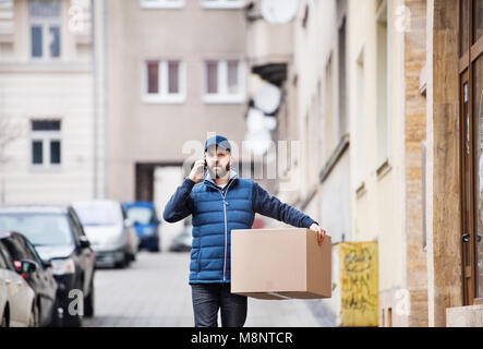 Delivery man with a parcel box on the street. Stock Photo