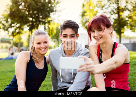 Group of young runners with a smartphone in a park. Stock Photo