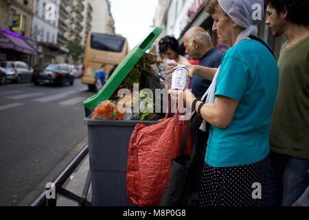 People Looking Through Food Waste Bin, outside supermarket, Rue de Clignancourt, Paris Stock Photo