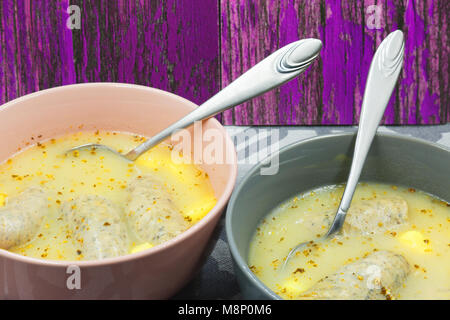 Two bowls of white borsch (Sour soup) with white sausage on wooden , vintage background. Traditional Easter soup in Eastern Europe. Close horizontal v Stock Photo