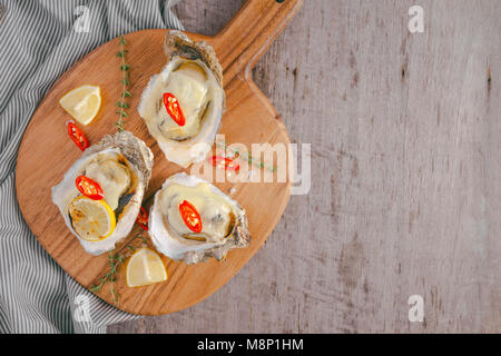 Fresh Oysters in shell with lemon on cutting board Stock Photo