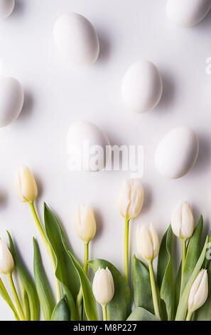 Flowers and white eggs on a white background. Flat lay. Stock Photo