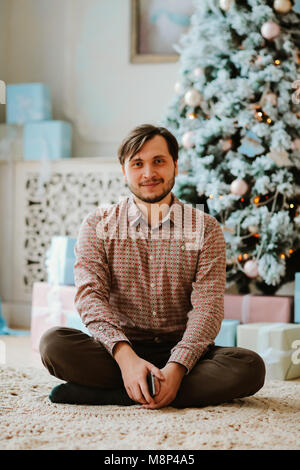 the guy is sitting on the carpet in a bright photo studio Stock Photo