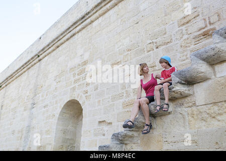 Mother and son sitting on the old city wall stairs in the Medieval town  Aigues Mortes in Camargue, Provence, France Stock Photo