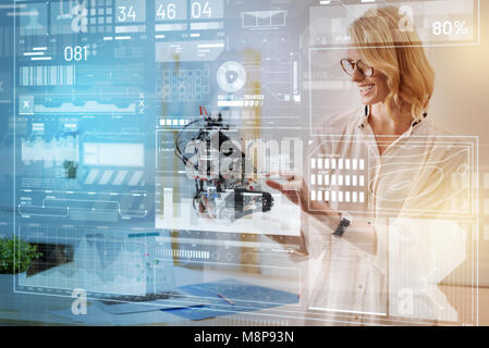 Successful engineer holding a little robot and looking delighted Stock Photo