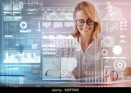 Positive young woman smiling while having a productive working day Stock Photo
