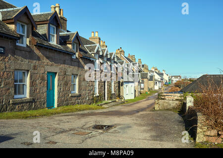 Sunlit row of welcoming holiday cottages by the jetty on Iona Argyll, Scotland Stock Photo