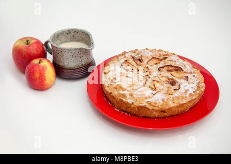 Apple cake with custard jug on a red plate. Stock Photo