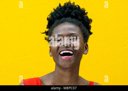 Portrait of a beautiful black colombian model laughing on a yellow monochrome background