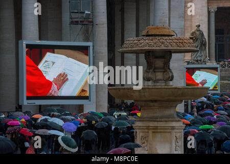 Vatican City. Faithful, holding umbrellas, look at a giant screen showing the start of the papal election conclave. Vatican. Stock Photo