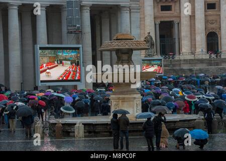 Vatican City. Faithful, holding umbrellas, look at a giant screen showing the start of the papal election conclave. Vatican. Stock Photo