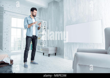 Concentrated brunette using his tablet Stock Photo