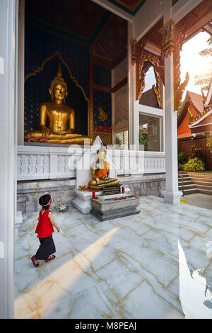 Small girl walking near Golden Buddha statue in Wat Saket at sunset in Bangkok, Thailand Stock Photo