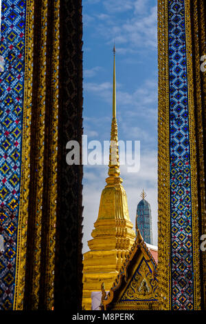 A golden pagoda is seen through the pillars of Prasat Phra Dhepbidorn, The Royal Pantheon, in The Grand Palace Stock Photo