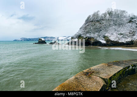 Snow covers the cliff tops around the St Austell Bay area of Cornwall as seen from Charlestown Harbour wall. Stock Photo