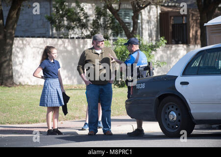 Curious residents talk to an Austin police officer as officials work the scene of a fourth package bomb in three weeks that exploded Sunday night in a southwest Austin neighborhood, injuring two men. Stock Photo