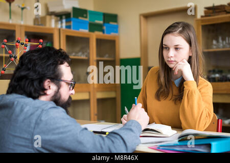 Young teacher helping his student in chemistry class. Education, Tutoring and Encouragement concept. Stock Photo